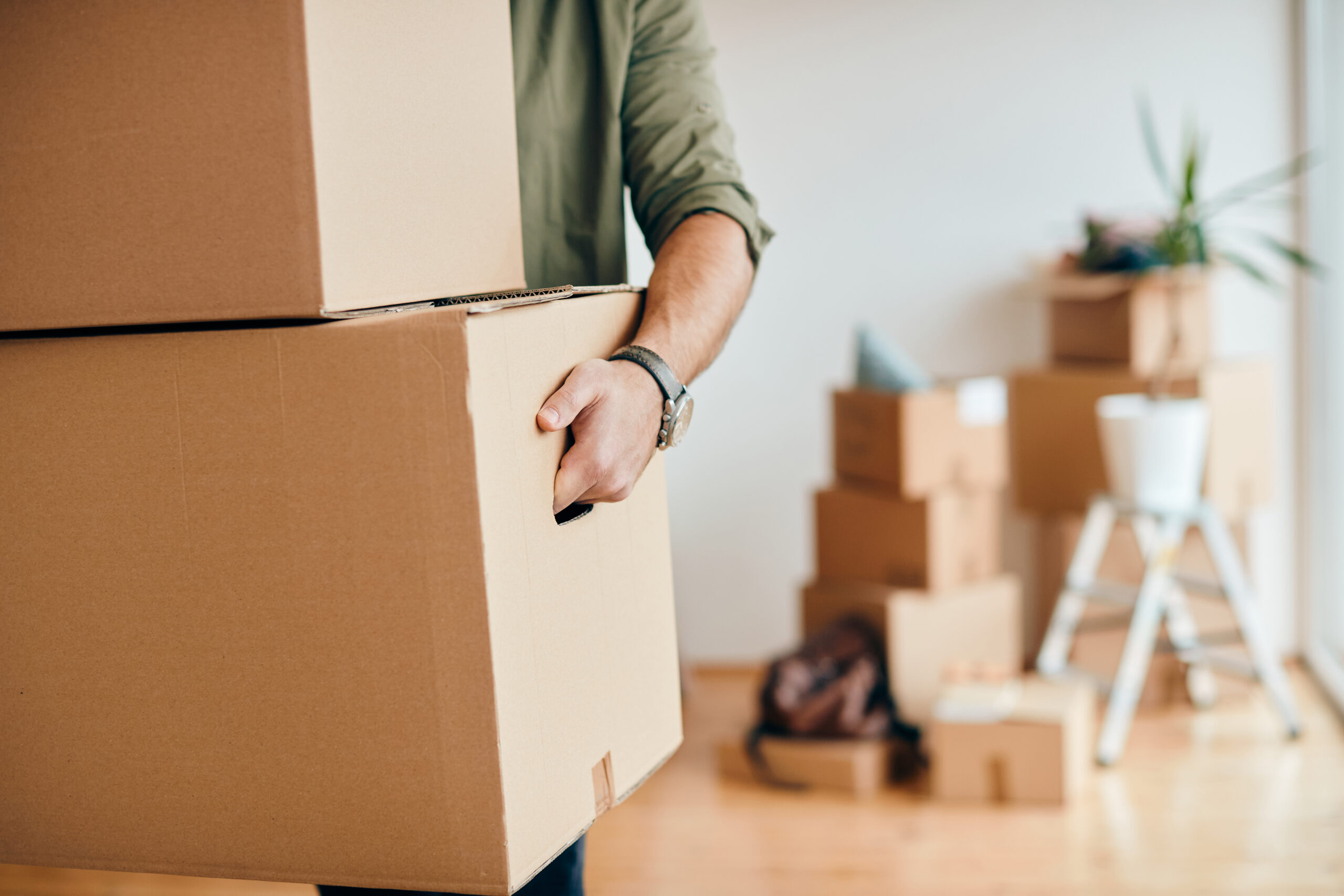 Close-up of a man with carton boxes moving into new home.